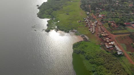 A-high-up-aerial-shot-looking-down-on-a-small-African-fishing-village-on-the-shores-of-Lake-Victoria-with-the-sun-reflecting-off-the-water