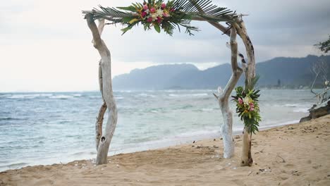 Still-shot-of-a-beautiful,-homemade-engagement-arch-found-on-a-sandy-Hawaiian-beach-on-Oahu