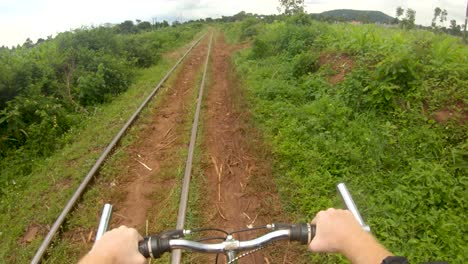 A-point-of-view-action-shot-looking-down-at-a-white-mans-hands-on-a-handle-bar-while-riding-a-bike-along-a-path-next-to-a-railway-in-Africa