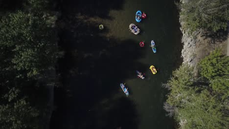 Tracking-aerial-view-rafts-floating-Boise-river-under-red-bridge