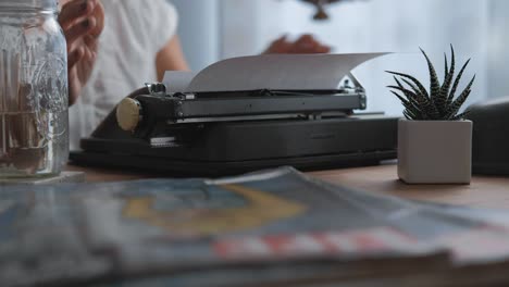 Medium-shot-rack-focus-from-life-magazine-to-woman-loading-paper-into-typewriter
