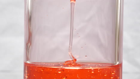 Rote-Abstrakte-Substanz,-Die-Auf-Flüssige-Oberfläche-Herunterfällt,-Beruhigender-Abstrakter-Hintergrund