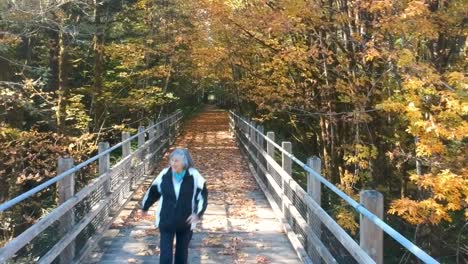 Happy-woman-skipping-on-a-trestle-path-in-autumn-in-Canada