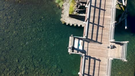 Drone-shot-moving-up-looking-down-at-woman-looking-down-in-the-river-off-a-trestle-in-Canada