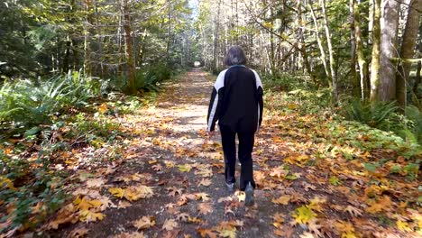Mujer-Caminando-Por-Un-Camino-Cubierto-De-Hojas-En-El-Bosque-En-Otoño-En-Canadá