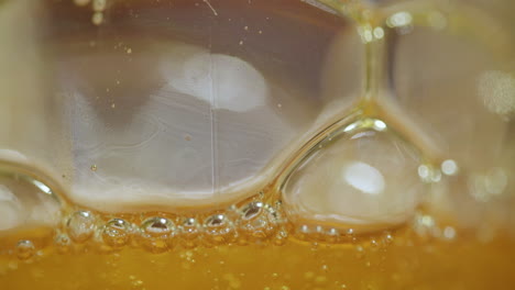 Macro-close-up-of-viscous-bubbles-expanding-and-floating-on-top-of-an-abstract-orange-liquid