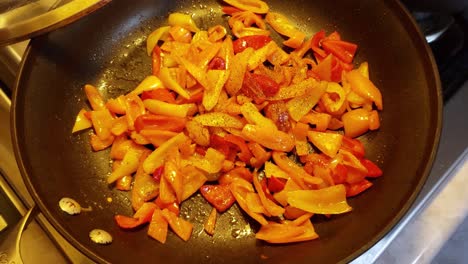 Colorful-peppers-being-sautéed-on-range-top-without-cover,-top-view
