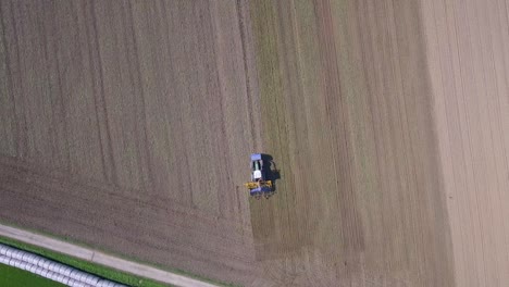 Toma-Aérea-De-Drones-Del-Tractor-Trabajando-Y-Cultivando-Tierras-Agrícolas