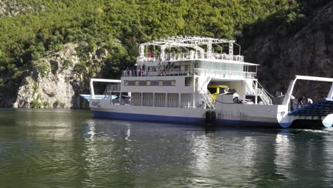 Ferry-Saliendo-De-Un-Pequeño-Puerto,-Llevando-Turistas-Que-Quieren-Visitar-Las-Altas-Montañas-De-Los-Alpes-En-Albania,-Los-Balcanes