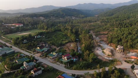 Aerial-shot-of-rural-village-surrounded-by-trees-and-closed-to-big-mountains