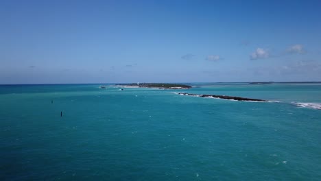 Windy-summer-morning-in-the-Caribbean-looking-out-on-the-turquoise-water-of-the-sea-and-small-islands-in-the-distance-with-waves-crashing-against-the-shoreline