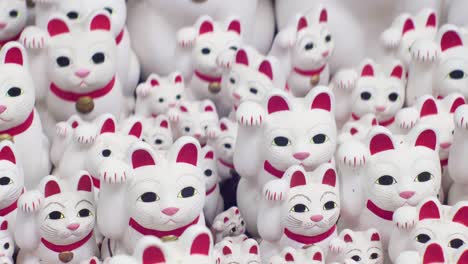 cute-white-maneki-neko-cats-in-gotokuji-tokyo,-tracking-right-shot
