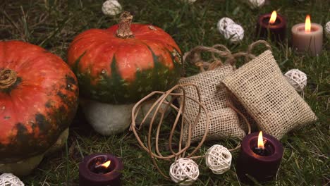 Herbstlicher-Hintergrund-Mit-Kürbissen-Und-Kerzen-Mit-Flammen,-Die-Sich-Im-Wind-Bewegen