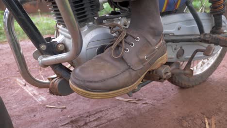 A-close-up-shot-of-a-African-mans-foot-changing-into-first-gear-on-a-motor-bike-and-riding-off