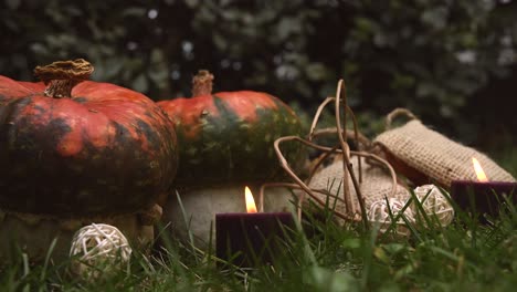 Herbstlicher-Hintergrund-Mit-Kürbissen-Und-Kerzen-Mit-Flammen,-Die-Sich-Im-Wind-Bewegen