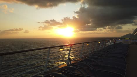 Unglaublicher-Sonnenuntergang-über-Dem-Meer-Mit-Liegestühlen-Entlang-Der-Reling-Eines-Kreuzfahrtschiffes