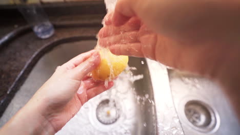 Female-hands-washing-a-potato-under-water-from-a-kitchen-tap-in-slow-motion