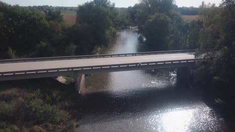 Point-of-view-slow-drone-flight-of-low-altitude-flight-over-a-bridge-crossing-Skunk-River-river-running-through-rural-Iowa-USA