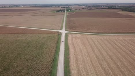 Vista-Aérea-De-La-Conducción-De-Camiones-Hacia-La-Intersección-De-Dos-Caminos-De-Grava-En-La-Zona-Rural-De-Iowa