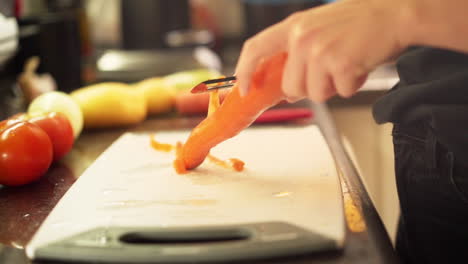 Cerrar-Las-Manos-Femeninas-Pelando-Zanahorias-En-La-Cocina-A-Cámara-Lenta