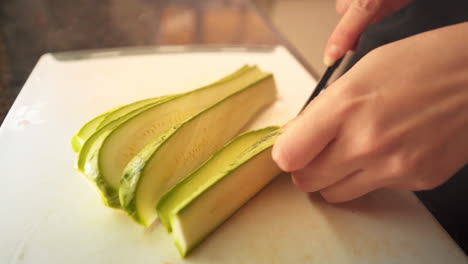 Female-hands-slicing-a-green-zucchini-in-the-kitchen-in-slow-motion