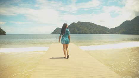 Epic-footage-of-a-girl-walking-on-a-jetty-with-the-sea-and-mountains-in-the-background