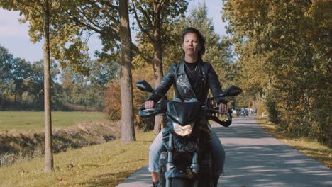 Frontal-view-of-beautiful-smiling-European-Female-motorcyclist-looking-into-the-camera-and-laughing