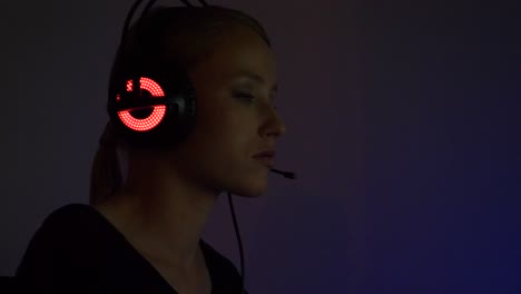 young-woman-playing-video-games-and-dissatisfied-talking-with-her-teammates,-neon-headset-and-dark-isolated-room-background