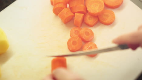 Female-hands-slicing-carrots-in-the-kitchen-cutting-board