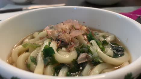 Moving-fish-flakes-over-a-hot-bowl-of-udon-noodles
