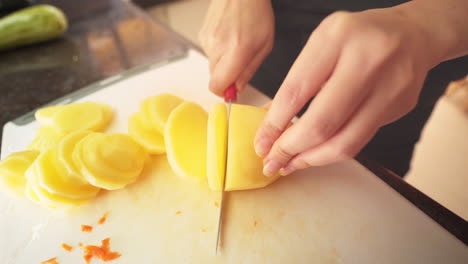 Female-hands-cutting-a-potato-in-the-kitchen-in-slow-motion