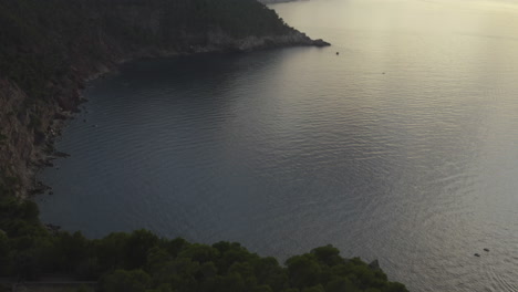 Aerial-tilt-reveal-of-the-foggy-horizon-at-dusk-on-the-rugged-coastline-of-Mallorca,-Spain