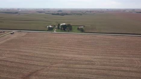 Vista-Aérea-De-Drones-De-Un-Campo-De-Maíz-Cosechado-Y-Una-Granja-Rural-De-Iowa-Con-Graneros