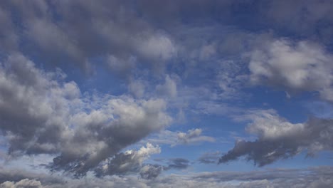 Time-lapse-view-of-puffy-grey-clouds-slowly-moving-forward-under-the-blue-sky