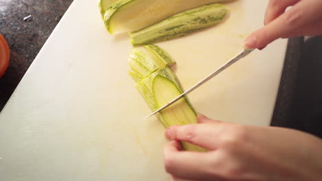 Female-hands-cutting-a-green-zucchini-in-the-kitchen-in-slow-motion