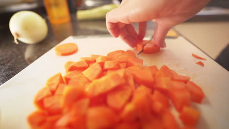 Female-hands-slicing-carrots-in-the-kitchen-on-a-cutting-board
