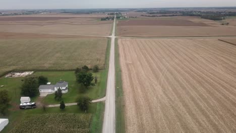 Aerial-flyover-view-following-a-gravel-road-towards-an-intersection-with-a-second-gravel-road-in-rural-Iowa