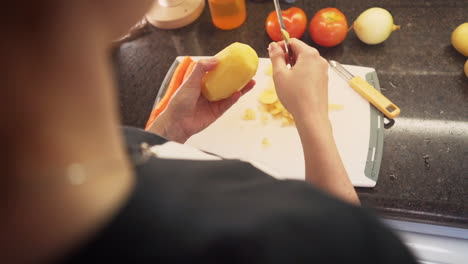 Female-hands-peeling-potatoes-in-the-kitchen-cutting-board