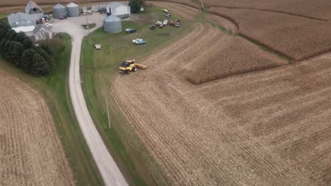 Drone-flyover-of-a-harvested-cornfield-towards-the-farmyard-with-grain-bins,-barns,and-other-farm-equipment-in-rural-Iowa