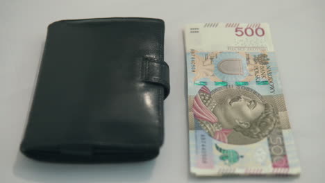 Panning-footage-from-right-to-left:-500-polish-zloty-with-black-wallet-on-table,-no-popular-money-in-country