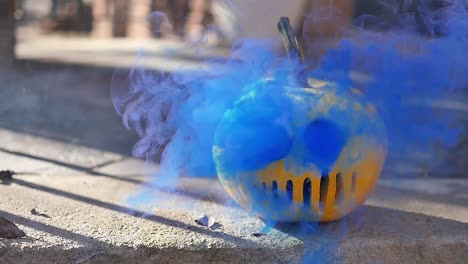 Hellblauer-Rauch,-Der-Aus-Einer-Kürbislaterne-Kommt,-Die-Wie-Eine-Serienmördermaske-Geschnitzt-Ist