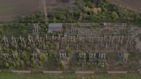 Desolate-decommissioned-nuclear-power-station,-over-grown-with-trees,-drone-dolly-forward