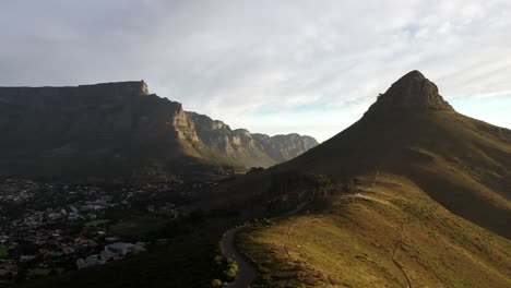 Aufsteigende-Filmische-Luftaufnahme-Des-Lion&#39;s-Head-Peak-Von-Kapstadt-Mit-Dem-Tafelberg-Und-Dem-Signal-Hill-Während-Des-Sonnenuntergangs-Zur-Goldenen-Stunde