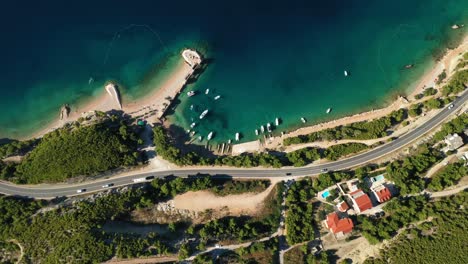 Aerial-drone-footage-of-cars-driving-on-a-coastal-road-across-the-screen-in-Croatia