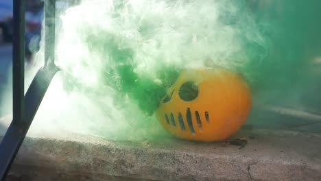 Slow-motion-of-green-smoke-coming-out-of-a-serial-killer-mask-jack-o-lantern-on-a-porch