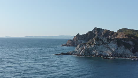 Vista-Panorámica-De-La-Costa-Con-Acantilados-Escarpados,-Rocas-Submarinas-Al-Atardecer