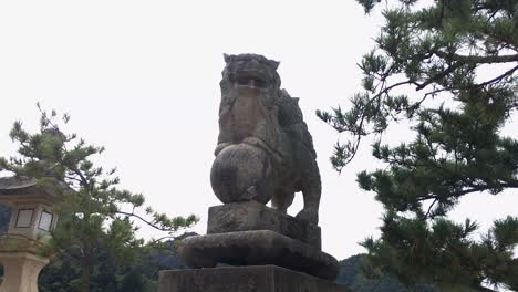 Una-Paloma-Vuela-Desde-Un-Komainu-En-Miyajima,-Japón