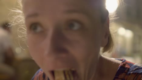 Close-up-of-a-young-blonde-woman-chewing-a-large-mouthful-of-pizza