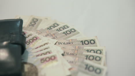500-polish-zloty-and-100-polish-zloty-lie-near-black-wallet-on-white-table