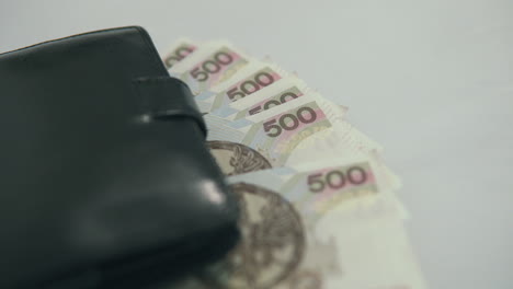 Paning-footage-from-left-to-right:-black-wallet-with-500-polish-zloty-lie-on-white-table